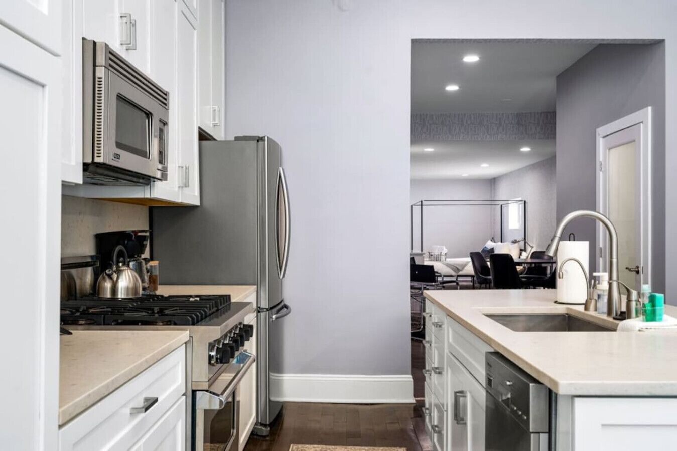 A modern kitchen with stainless steel appliances, a central island with a sink, and a view into the dining area.