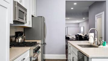 A modern kitchen with stainless steel appliances, a central island with a sink, and a view into the dining area.