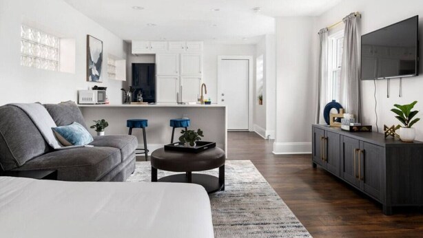 Een moderne woonkamer met een bank, salontafel en een aan de muur bevestigde televisie.