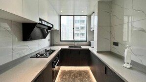 Une cuisine moderne dotée d’un îlot central, d’une cuisinière intégrée et d’une fenêtre offrant une vue sur la ville.