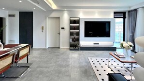 Un salon moderne avec un téléviseur à écran plat, un piano et une table basse.