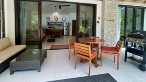 Ein modernes Wohnzimmer mit Sofa, Esstisch, Stühlen, Küchenzeile und Grill.