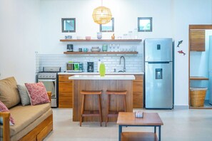 A compact kitchen with a central island, a refrigerator, a stove, and a sink.
