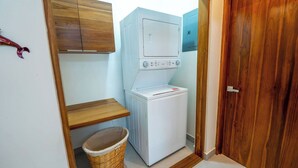 A laundry room with a washing machine and dryer, wooden cabinets, a wicker basket, and a wooden door. - Bright and Tropical Casa Mar, Playa Pelada, Nosara (NICOYA)