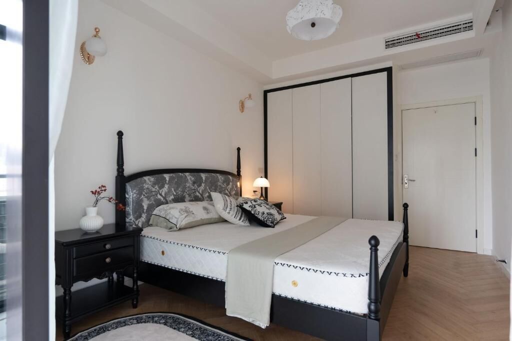 A bedroom with a bed, nightstand, lamp, and wardrobe.