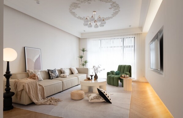 Ein modernes Wohnzimmer mit einer Couch, einem grünen Sessel, einem runden Couchtisch und einer Deckenleuchte.