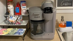 A kitchen with a Keurig coffee maker, coffee pods, sugar, and a coffee grinder. - Charming 2-bedroom house in Bay St. Louis with WiFi and AC (Bay St. Louis)