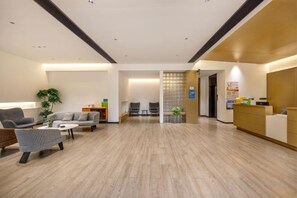 A modern hotel lobby with a reception desk, seating area, and a plant. - Tianfu Hotel (Xianju)