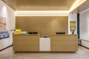 A reception desk with a flat surface, a small fan, and a plant on the right. - Tianfu Hotel (Xianju)
