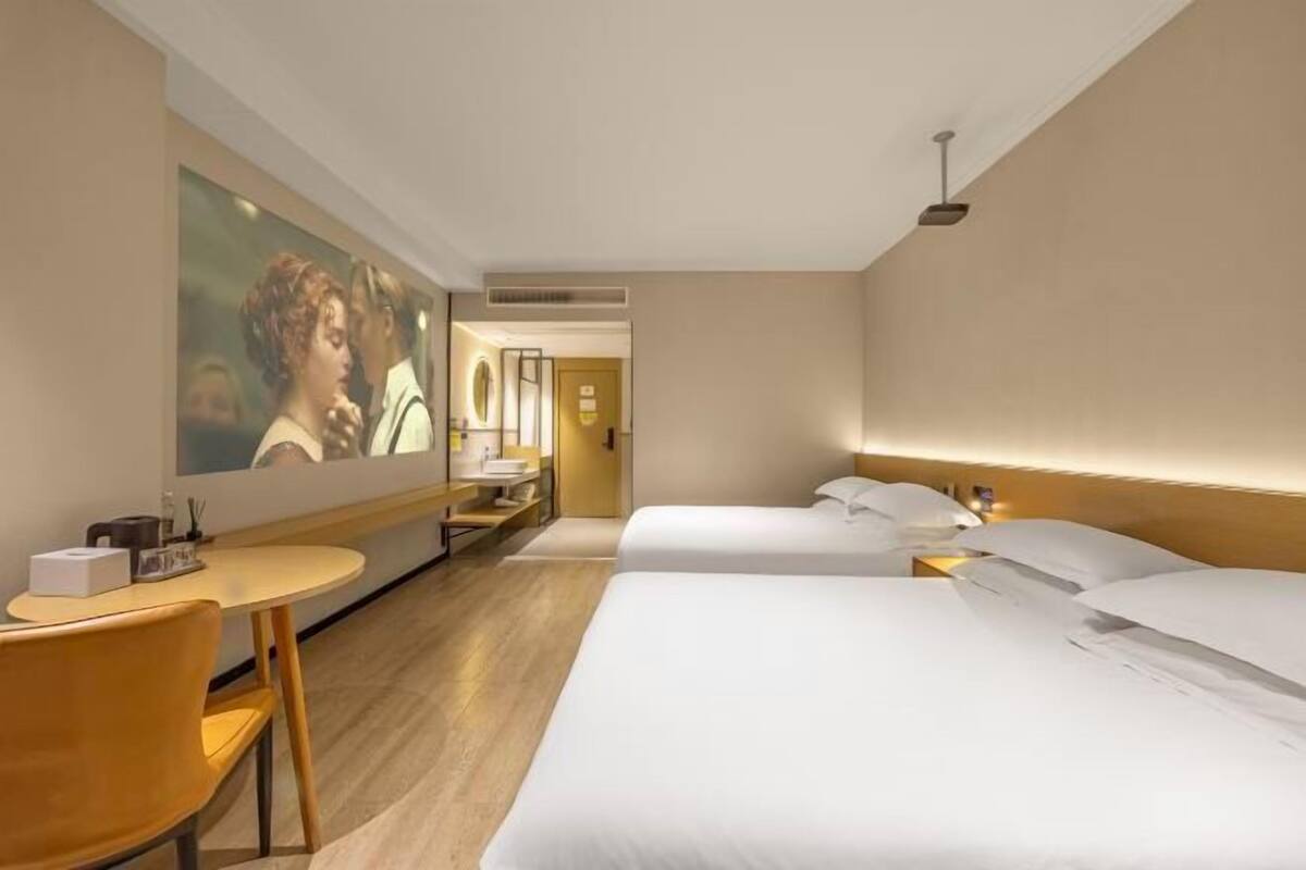 A hotel room with a bed, a desk, a chair, and a mirror.