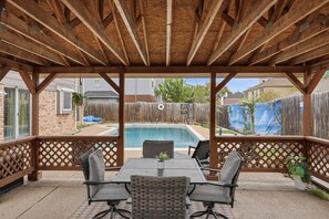 Un patio couvert avec une piscine, du mobilier d’extérieur et un plafond en bois.