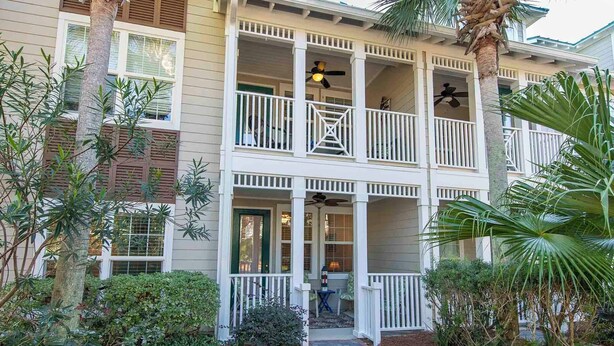 A two-story building with a covered porch, multiple balconies, and a pathway leading to the entrance. - The Village #611 by Southern Vacation Rentals (Santa Rosa Beach)