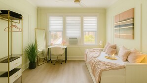 A bedroom with a bed, a desk, a chair, a mirror, a wardrobe, and a ceiling fan.