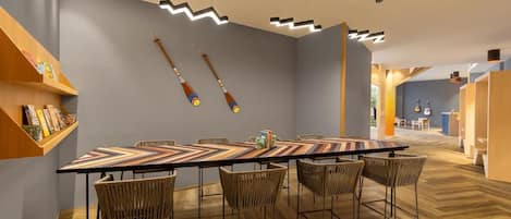A modern dining area with a long table, wicker chairs, and a geometric-patterned tablecloth.