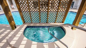 Un espace piscine agrémenté d’une clôture en treillis de bois, d’un jacuzzi et de chaises longues.