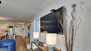 Un salon moderne avec un canapé bleu, une table basse en bois agrémentée de deux lampes et un élément décoratif mural.