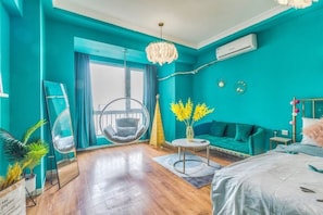 A teal-themed room with a hanging chair, a sofa, a small round table, and a bed. - Xi'an Homestay (Xi'an)
