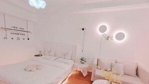 Ett modernt hotellrum med en stor säng, en soffa, ett litet runt bord och en projektor som är monterad på väggen.