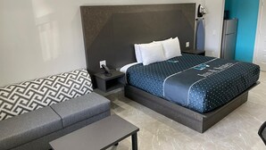 Ein modernes Hotelzimmer mit einem großen Bett, einer Couch, einem kleinen Tisch und einem Nachttisch.