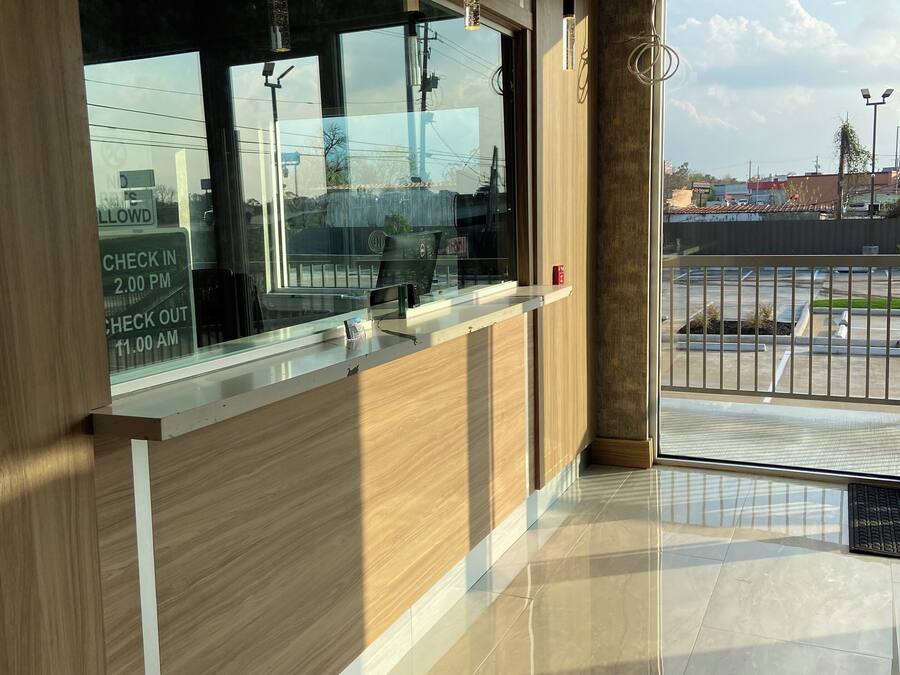 A modern reception area with a wooden reception desk, a glass window, and a view of the parking lot.