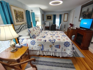 A hotel room with a bed, a desk, a chair, a TV, and a fireplace. - Digby B&B (Digby)
