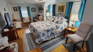 Une chambre bien éclairée, avec un lit, une chaise, un bureau et un téléviseur.
