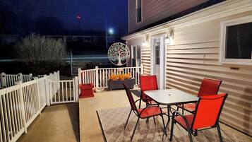 A patio with a table and chairs, a decorative tree sculpture, and a white fence.