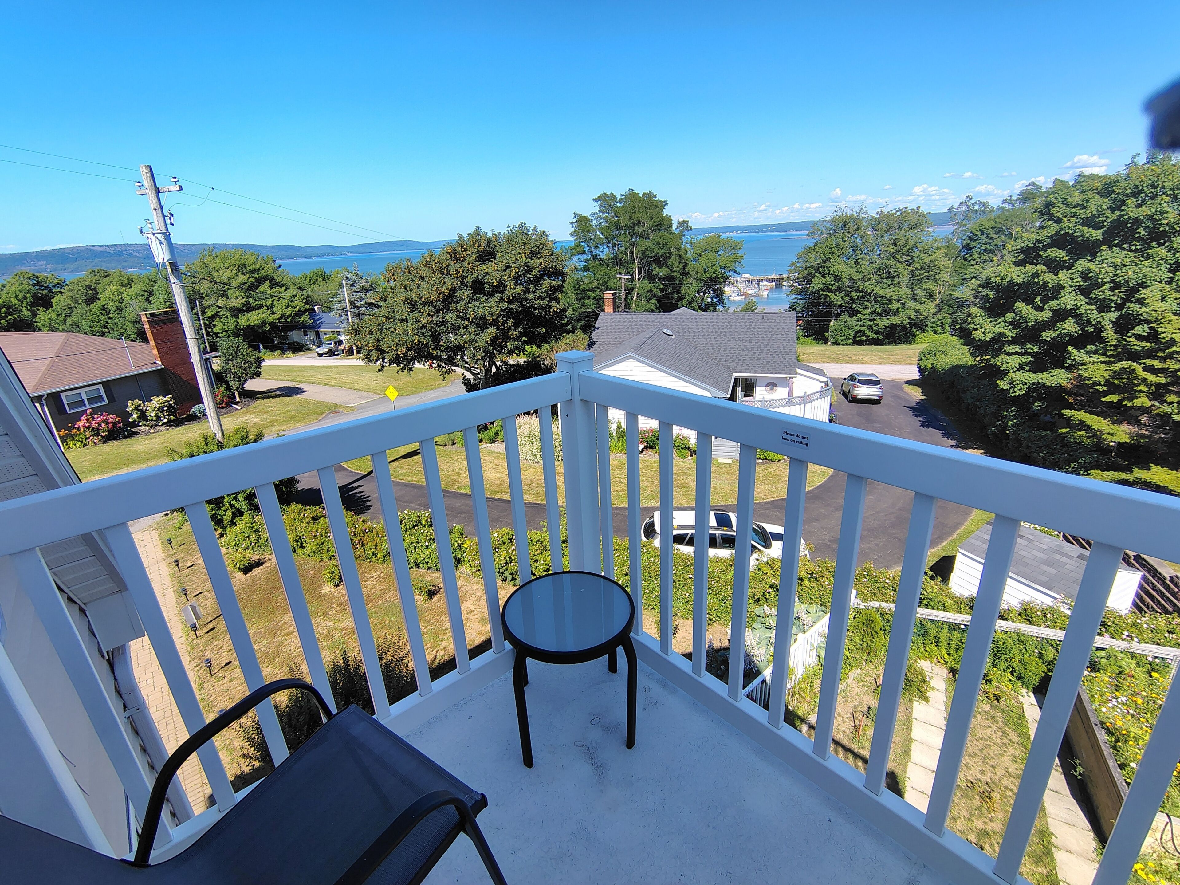 A balcony with a view of a residential area, a small table, and a chair.