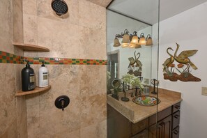 Un baño con ducha, tocador con espejo y decoración en la pared.