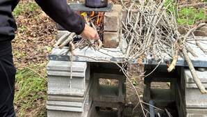Een draagbaar fornuis met een pan op een stenen platform, gelegen in een bos.