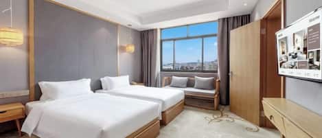 A hotel room with two beds, a desk, a TV, and a window with a city view.