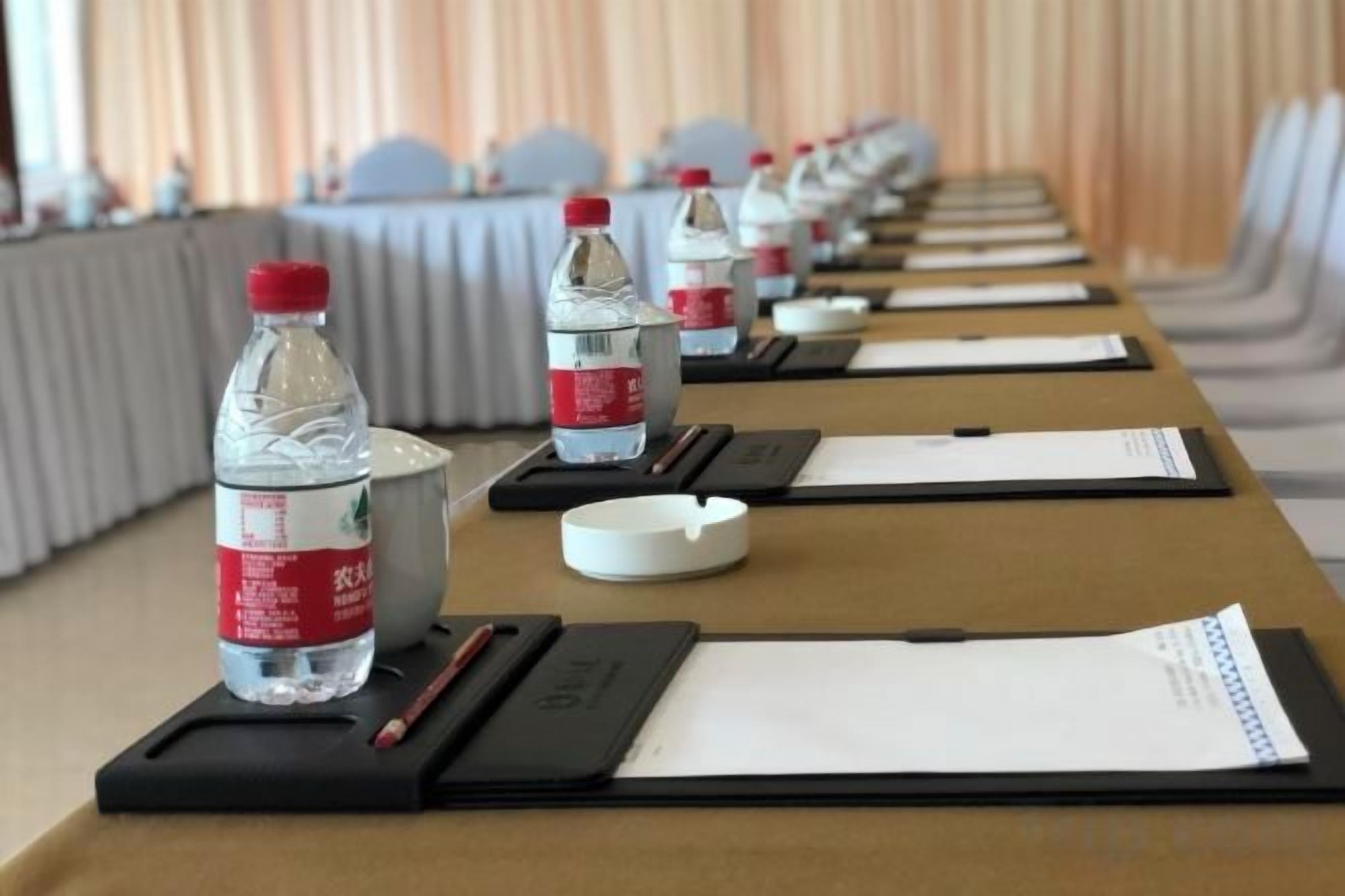 A conference room with tables set up with water bottles, notepads, and pens.