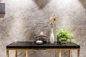 A marble wall, a black table with gold legs, and a potted plant.