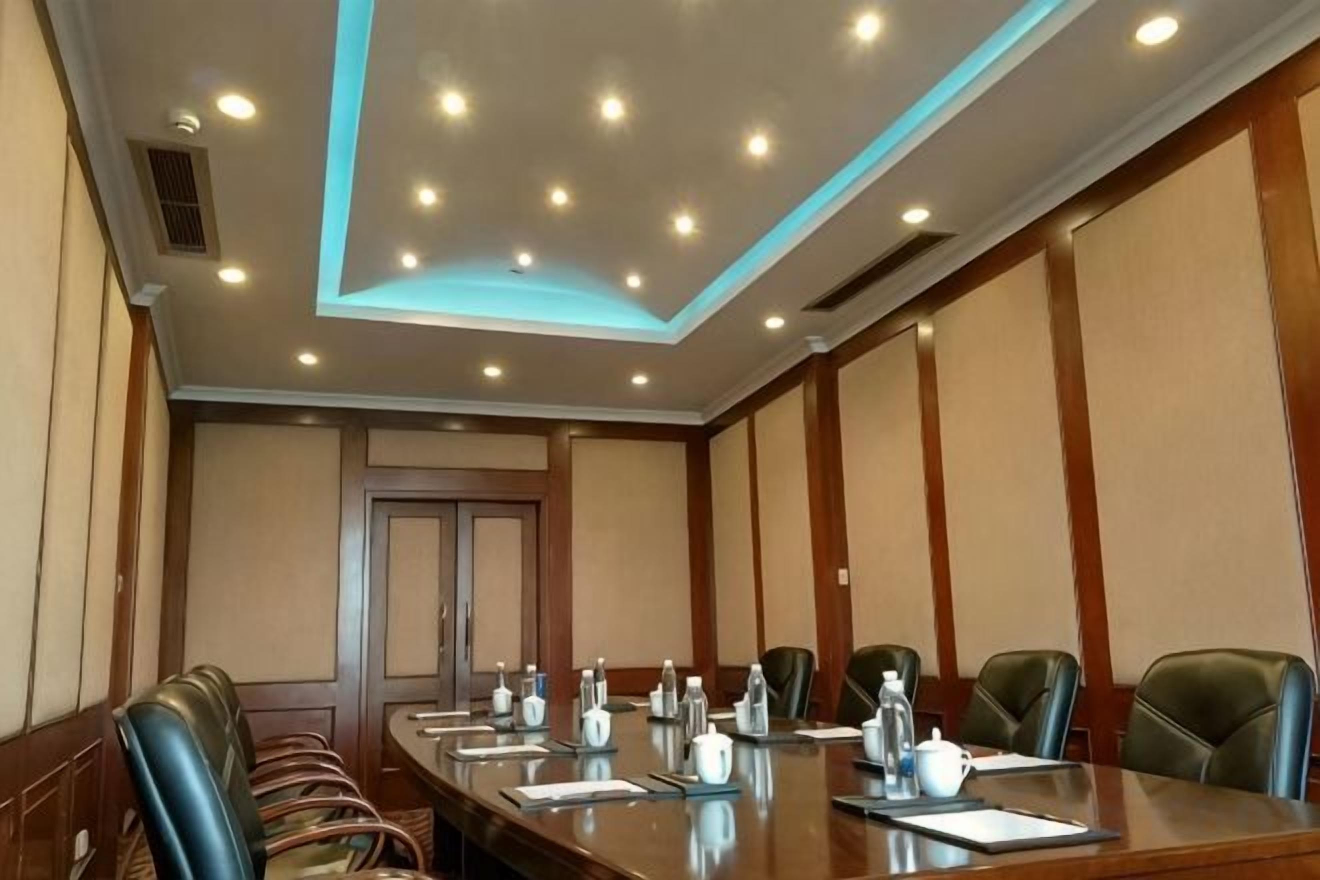 Una sala de conferencias con una larga mesa, sillas y varios servicios como botellas de agua y blocs de notas.