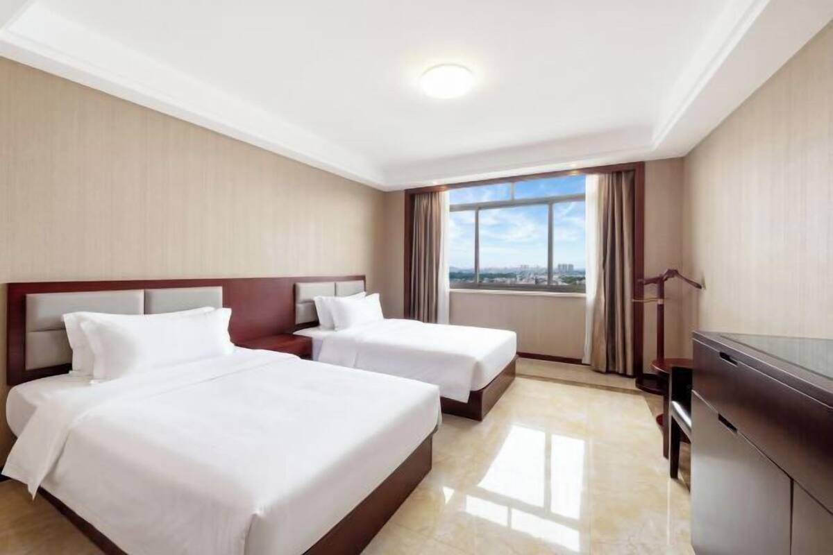 A hotel room with two beds, a TV, and a view of the city.