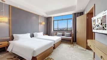 Una habitación de hotel con dos camas, un escritorio, un televisor y una ventana con vista a la ciudad.