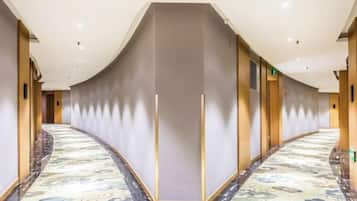 Un pasillo de hotel con una pared curva, una alfombra estampada y un diseño moderno en el techo.
