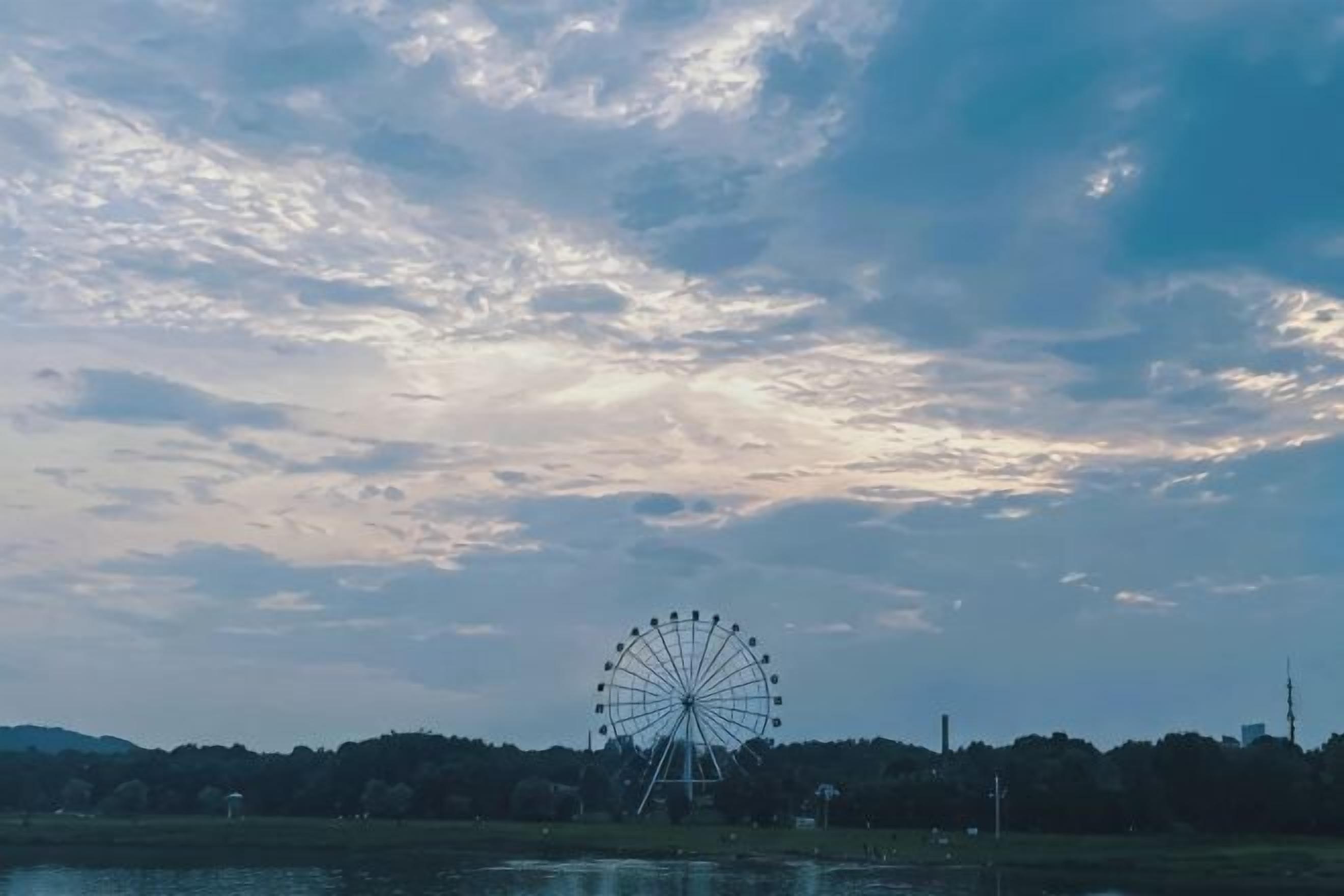 Ein Riesenrad vor einem bewölkten Himmel.