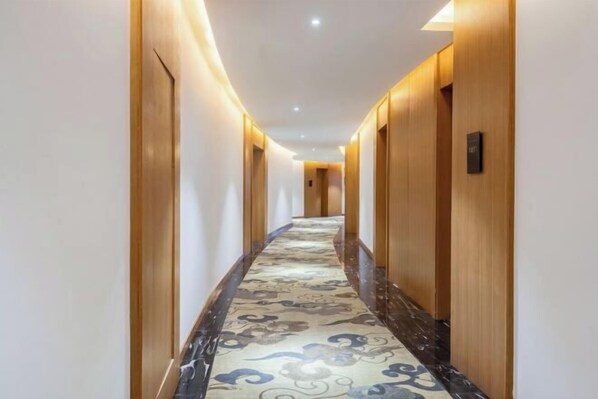 A long, narrow hallway with wooden doors and a patterned carpet. - Lanjiang Hotel (Lanxi)