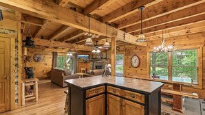 A wooden cabin interior with a kitchen island, wooden floors, and a fireplace. - Cabin for 12 | 10 mins to Pkwy w/ Hot Tub & Games! (Sevierville)