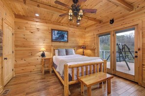 A wooden cabin room with a bed, bedside table, lamp, and a bench. - 5BR Cabin w/ Mountain Views, Hot Tub & Game Room! (Sevierville)