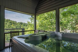 A hot tub on a wooden deck with a view of a forest. - 5BR Cabin w/ Mountain Views, Hot Tub & Game Room! (Sevierville)