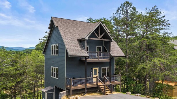 A two-story house with a balcony, a front porch, and a driveway. - Modern Cabin w/ Pool, Hot Tub, Games & More! (Sevierville)