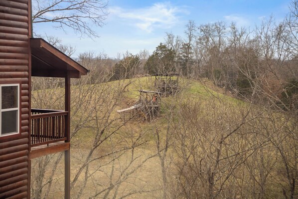 Une cabane en bois dotée d’un balcon donnant sur une zone boisée.