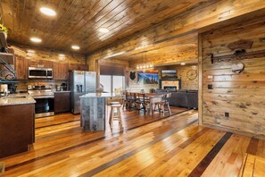 Une cuisine spacieuse dotée de meubles en bois, d’un îlot central et d’un coin repas avec une grande table et des chaises.
