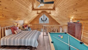 Une pièce confortable avec un lit, une table de billard et un ventilateur de plafond.