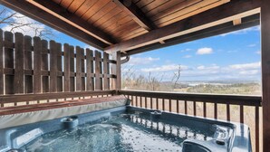 Un bain à remous sous une pergola en bois, avec vue sur un paysage aride.