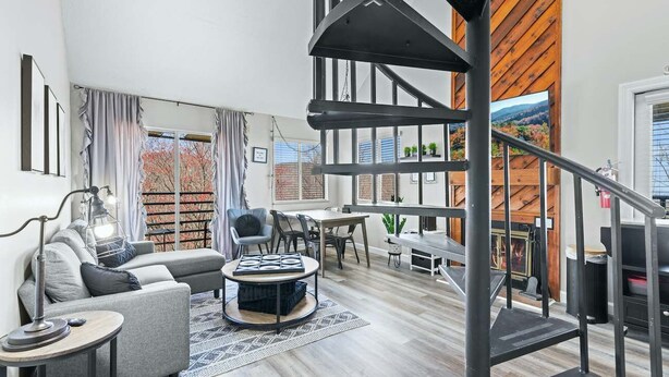 A modern living room with a spiral staircase, a sofa, a coffee table, and a fireplace.