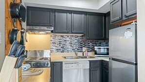 A modern kitchen with dark cabinets, stainless steel appliances, and a tiled backsplash.