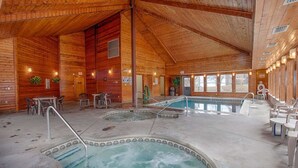 A wooden cabin with a hot tub, a pool, and outdoor seating.